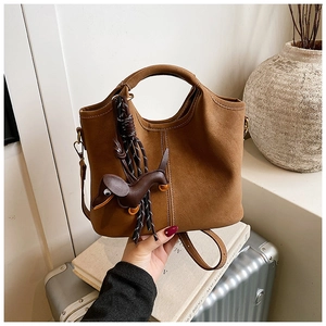 Close-up of vintage brown matte bucket bag with a dog pendant and white stitching detail