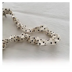 Close-up of ruffled cream shoulder strap with black polka dots and silver metal zipper