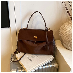 Detailed shot of dark brown suede crossbody bag with gold buckle on artistic backdrop