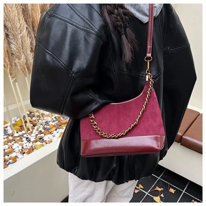 Detail of burgundy patchwork shell bag with suede finish and gold chain strap