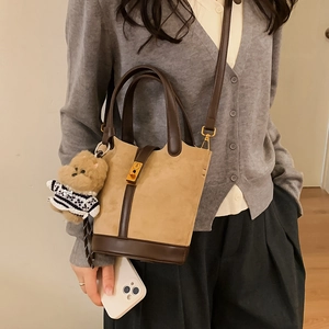 Détail du sac seau marron avec fermoir doré et porte-clés ours en peluche à rayures