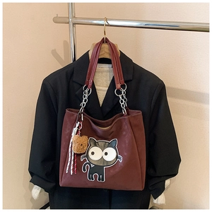 Détail du cabas bordeaux avec écusson chat et bandoulière en chaîne et cuir