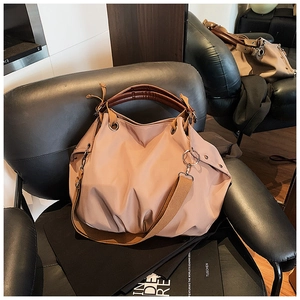 Detail of hobo style pink nylon tote bag with leather handles and adjustable strap