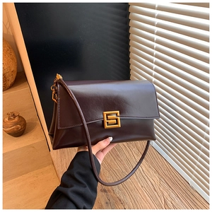 Detailed view of dark brown leather shoulder bag with a gold geometric metal buckle