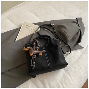 Detail of black matte bucket bag with white contrast stitching and dachshund charm