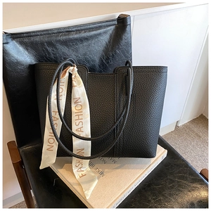 Nahaufnahme der schwarzen Tote-Bag aus genarbtem Leder mit modischem Seidenschal-Detail