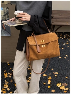 Detail of caramel suede tote bag with gold swivel lock and slim handle on park bench