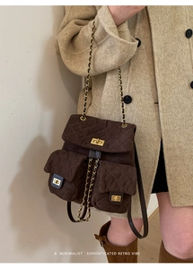 Detail of dark brown quilted suede backpack with gold twist locks and chain straps