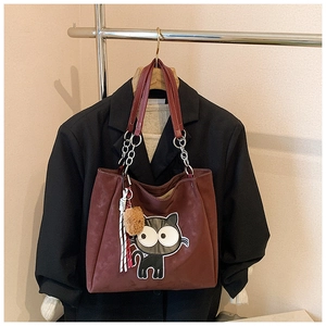Détail du sac cabas rouge-brun avec broderie chat cartoon et breloque pompon en fourrure