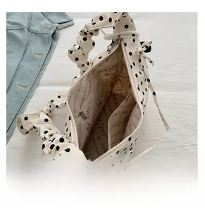 Close-up of cream polka dot handbag showing interior lining, inner pocket and zip closure