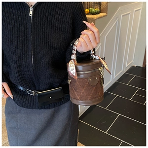 Detail of coffee cylinder bucket bag with quilted suede and decorative silk scarf