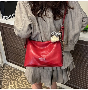 Detail of red vintage leather crossbody bag featuring a plush bear and leopard bow