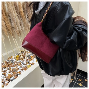 Detail view of burgundy crescent bag with matte suede splicing and gold chain strap