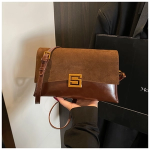 Close-up of retro brown crossbody bag with suede stitching and golden square buckle