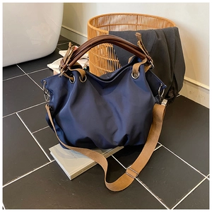 Detail of navy nylon tote bag with brown handles and adjustable khaki wide strap