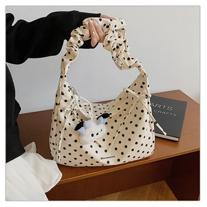 Close-up of pleated shoulder strap and polka dot canvas bag with cloud charm