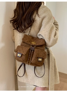 Close-up of quilted suede backpack showing gold twist lock and retro chain strap details