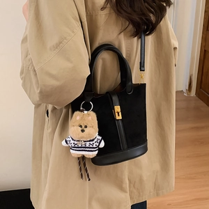 Détail du sac seau noir en daim avec fermoir doré et breloque ours sur modèle