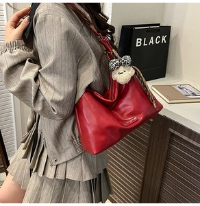 Detail of red oil-wax leather shoulder bag with leopard bow and plush puppy pendant