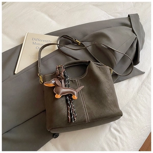 Detail of dark brown matte bucket bag with white contrast stitching and dachshund charm