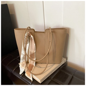 Detailansicht der khakifarbenen Ledertasche mit Kieselstruktur und modischem Seidenschal