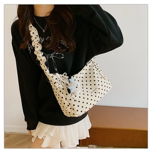 Detailed view of cream polka dot shoulder bag with ruffled strap and plush charm