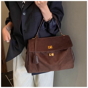 Detail of a large dark brown suede tote bag featuring dual gold twist-lock closures