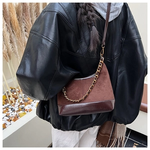 Brown patchwork shell bag with suede texture and gold chain strap shown on person