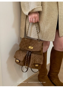 Detail view of quilted brown suede backpack with gold chain straps and metal turn locks