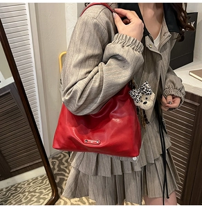 Close-up of red hobo bag with shiny leather finish and cute leopard bow bear charm