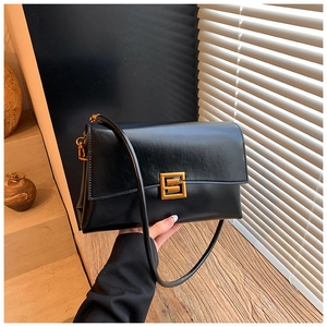 Detail shot of vintage black leather shoulder bag featuring a sleek gold geometric buckle
