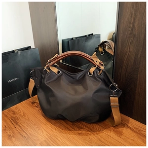 Detail of black nylon hobo bag with brown leather handles and detachable shoulder strap