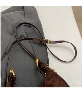 Détail du sac bandoulière en daim marron foncé avec sangle réglable et garnitures dorées