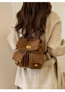 Macro detail of brown quilted suede backpack with gold hardware and chain straps