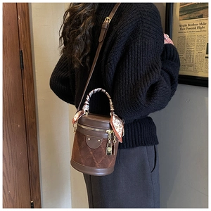Close-up of brown bucket bag with quilted suede panel and silk scarf on handle