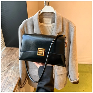 Detail of a vintage black leather shoulder bag with a gold geometric metal buckle