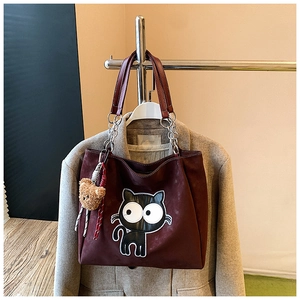 Vue détaillée du sac cabas bordeaux avec écusson chat et breloque ours en peluche
