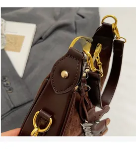 Détail d'un sac à main en daim marron foncé avec anneaux dorés et pendentif Love argenté