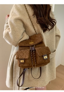 Detail of vintage brown quilted suede backpack with gold chain straps on a model