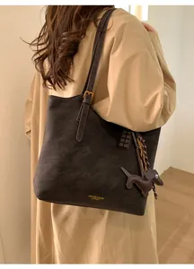 Detail of dark brown tote bag with leather tassel and cute puppy charm accessory