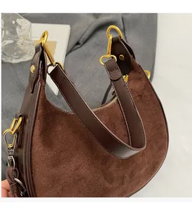 Détail du sac hobo en daim marron rétro avec garniture en cuir et boucles dorées