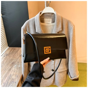 Close-up of black leather shoulder bag with gold square metal lock and vintage minimalist design