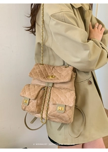 Detail of khaki suede quilted backpack featuring gold chain straps and metal twist lock