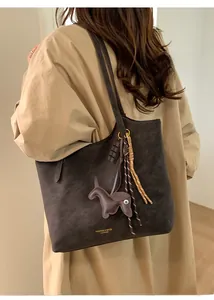 Close-up of leather tote bag with FASHION & BAGS lettering and horse charm accessory