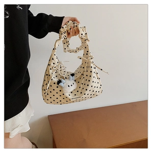 Detail of cream polka dot tote bag with ruffled handle and plush puppy pendant