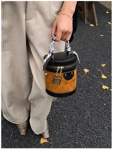 Detail of a cylinder bag with diamond stitching and a heart-patterned silk scarf handle