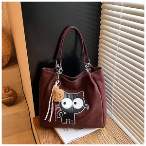 Détail macro du cabas en daim bordeaux avec patch chat de dessin animé et pompon