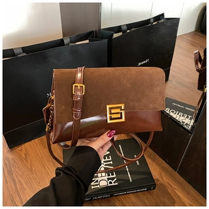 Macro shot of retro brown patchwork shoulder bag with gold S-buckle and suede flap