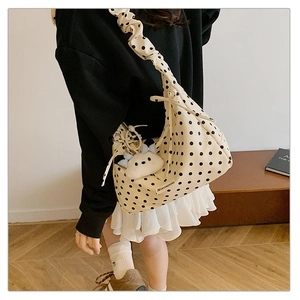 Detail of beige polka dot shoulder bag featuring pleated strap and cute plush charm