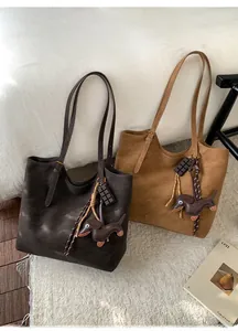 Detail of vintage large capacity tote bags in dark brown and caramel with puppy charms